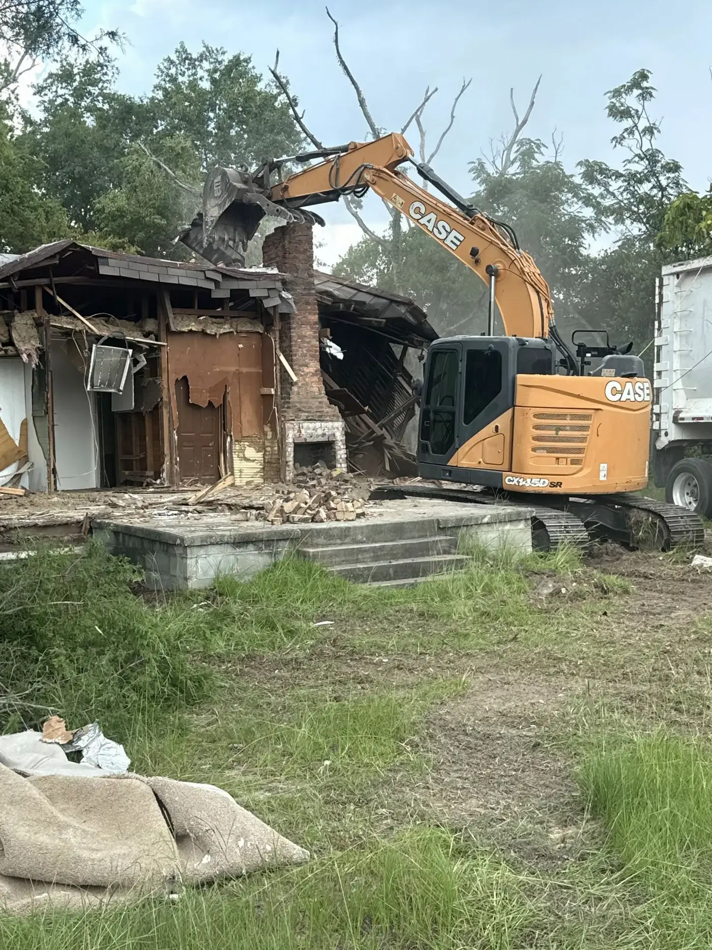 CASE excavator pulling down a brick chimney on a house demolition
